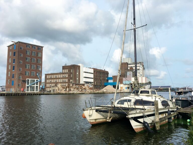 vooraanzicht van een witte catamaran aan de steiger in de zaanstreek met fabrieken op de achtergrond