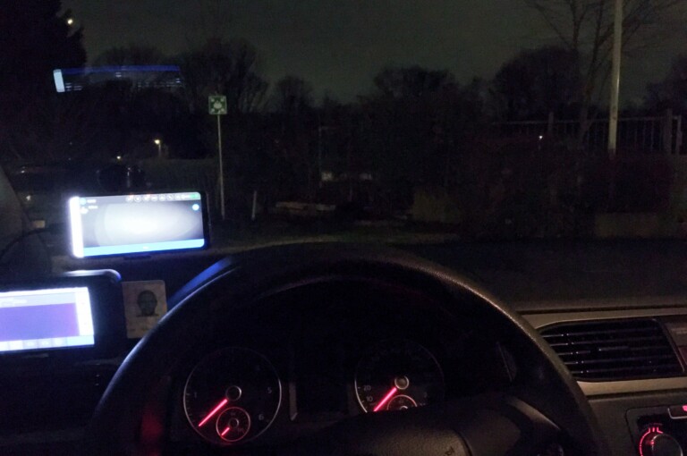 Uitzicht vanuit mijn voorruit. Deze keer op een wat minder verlichte plek buiten de stad dus het is vooral donker. Alleen maar wat siloetten van bomen.