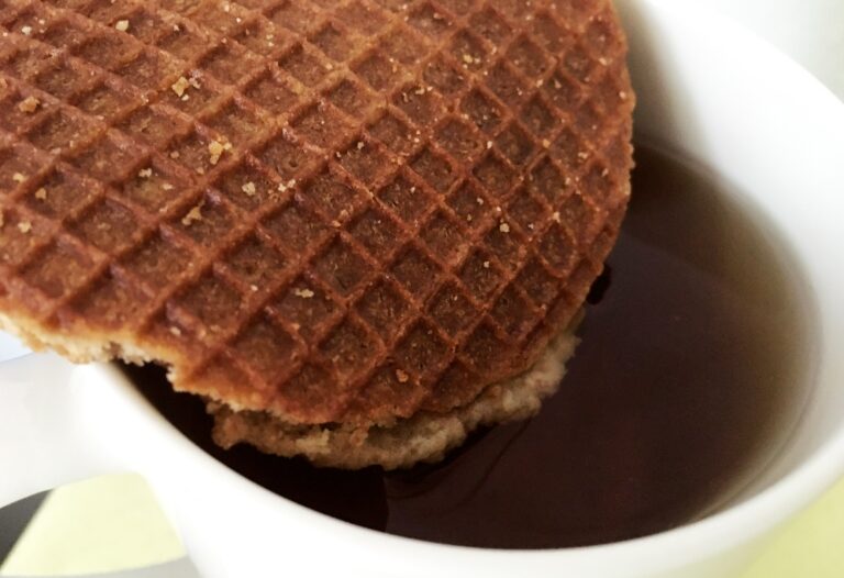 Een stroopwafel die boven een kop thee hangt en langzaam in de thee buigt