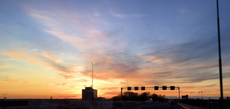 Mooie oranje zonsondergang vanaf de A9 bij het Amsterdamse Bos. Met wat uitgewaaide wolken en blauwe lucht