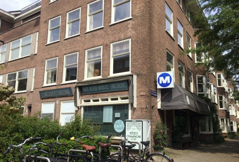 Een foto van een typisch gebouw van 4 verdiepingen in de rivierenbuurt in Amsterdam. Op de hoek zit "Alles voor Lunch". 