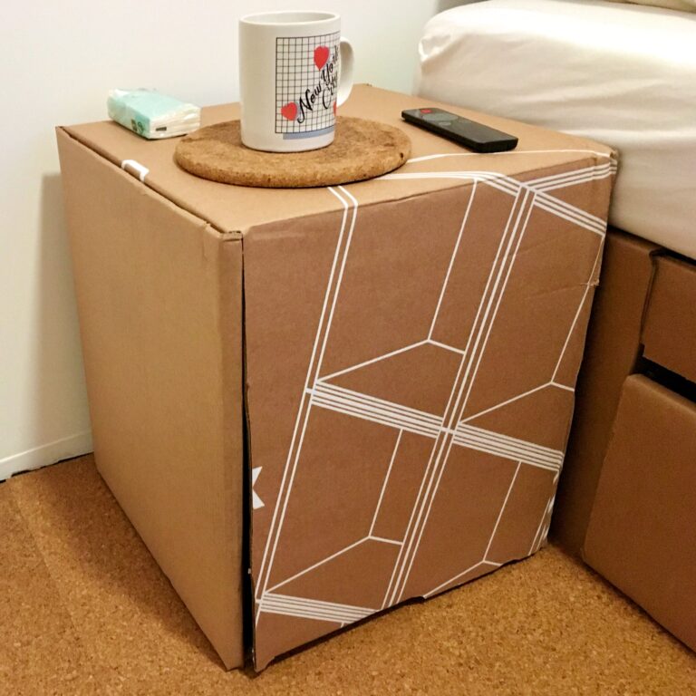 Foto van het gemaakte kartonnen tafeltje met daarop een mok met de tekst "New York City" uit de jaren 80 denk ik. En pakje zakdoeken en de afstandbediening van de infraroodkachel.