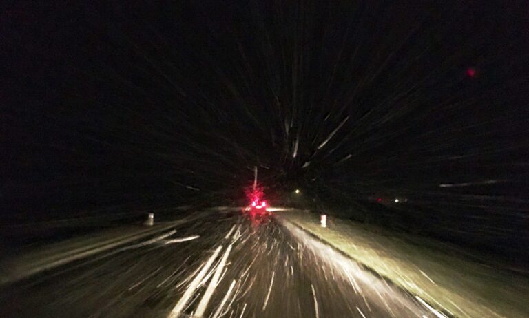 Sneeuwbui vanuit de voorruit gefotografeerd. Het wordt net een tunnel waar je doorheen rijdt.