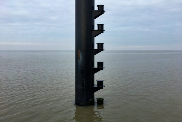 De kalme Waddenzee met een meerpaal in het midden