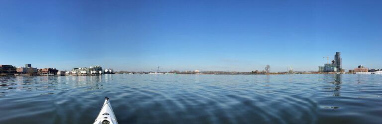 Panorama midden op het uitgestrekte stille blauwe Zeeburger water (en geen bootje te bekennen terwijl het zondag is!). Links het Zeeburger eiland met de nieuwe flatgebouwen en rechts het KNSM eiland.