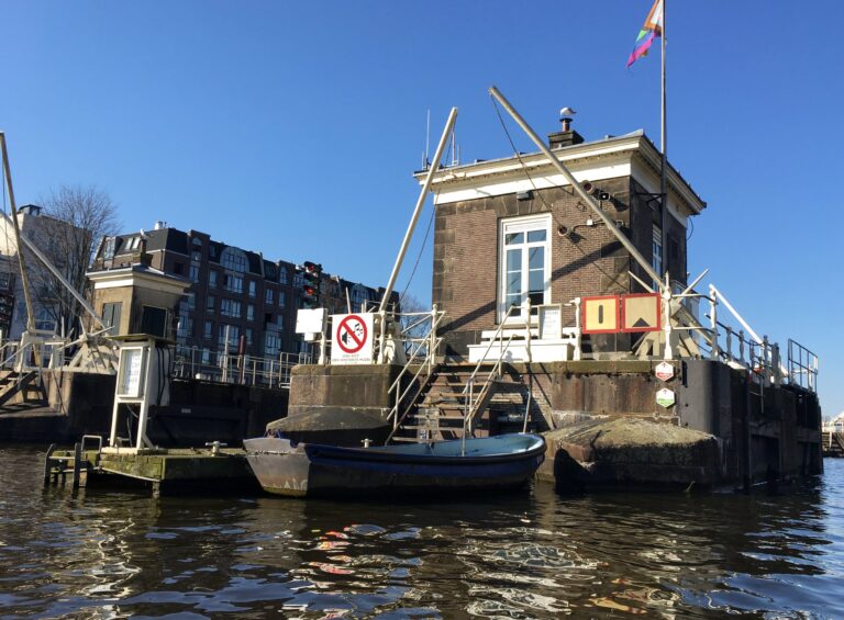 He sluithuisje op het midden van de Amstel in Amsterdam. Rustig water en blauwe lucht. En een roeibootje om naar de wal te kunnen varen.