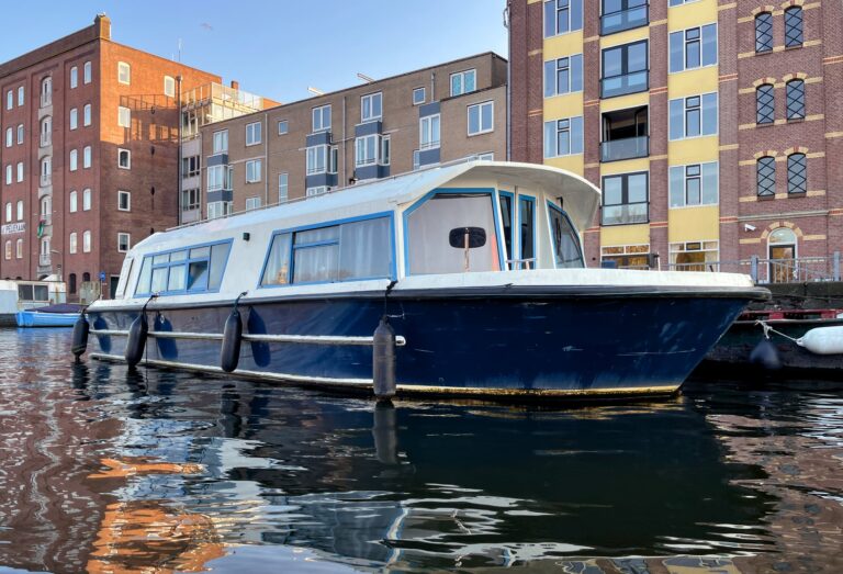 Bootje wat lijkt op een oude rondvaartboot. Laag dus past onder de vaste bruggen door. Maar ingericht als woonboot schat zo'n 6 mater lang.