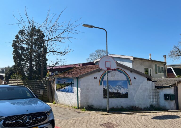 Klein gebouwtje met witte muren met daarop weer foto's van een berglandschap, een weiland. En er is ook een losse regenboog met wat vlinders op gezet. Aan ht gebouwtje zij weer andere kleine gebouwtjes oragnisch aan vast gebouwd. Het voelt knus.