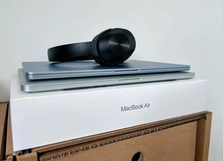 Een foto van mijn de MacBook AIr door met daarop de oude MacBook Pro en daarop de nieuwe MacBook Air (net iets kleiner en blauwer) met daarop zwarte koptelefoon.