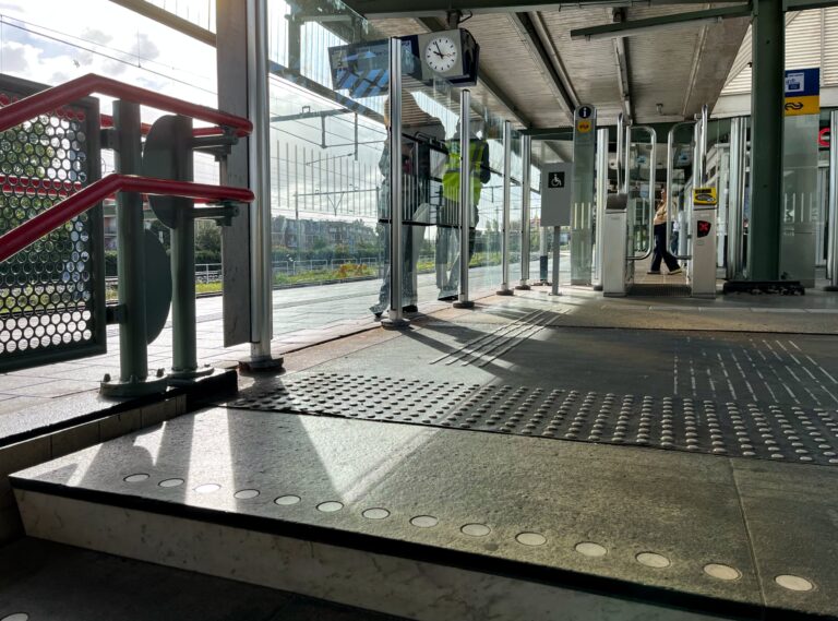 Treinstation amsterdam Muiderpoort bij spoor 3. Kom net de trap oplopen en die kan je ook nog een beetje zien. Er staan een aantal mensen te wachten. De zon schijnt.