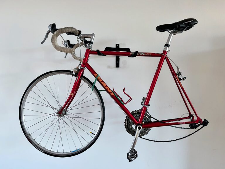 klassieke rode racefiets hangt aan de witte muur en mist zijn achterwiel