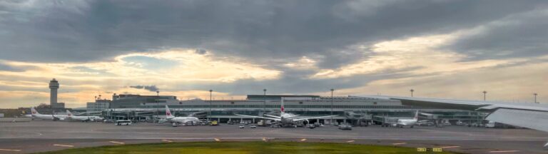 uitzicht vanuit het vliegtuig tijdens het taxien bij new chitose airport in Japan. Beetje troosteloos plat gebouw met een zwerm vliegtuigen eromheen