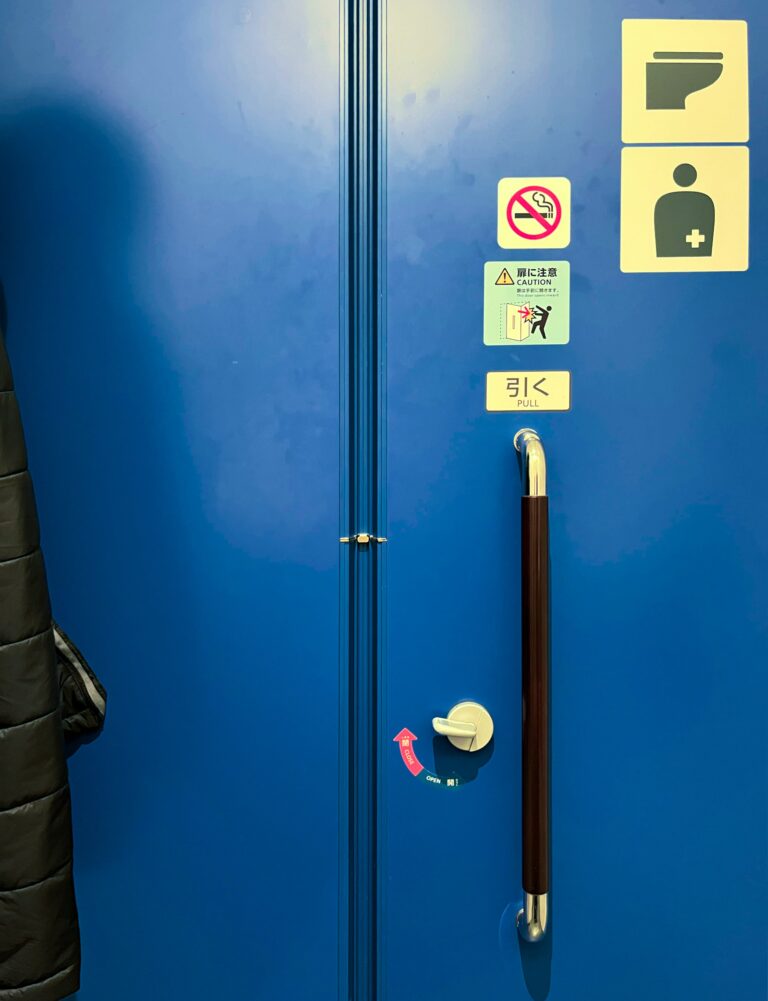 Waarschuwingen op de blauwe deur van het toilet om te zorgen dat je 'm juist gebruikt.