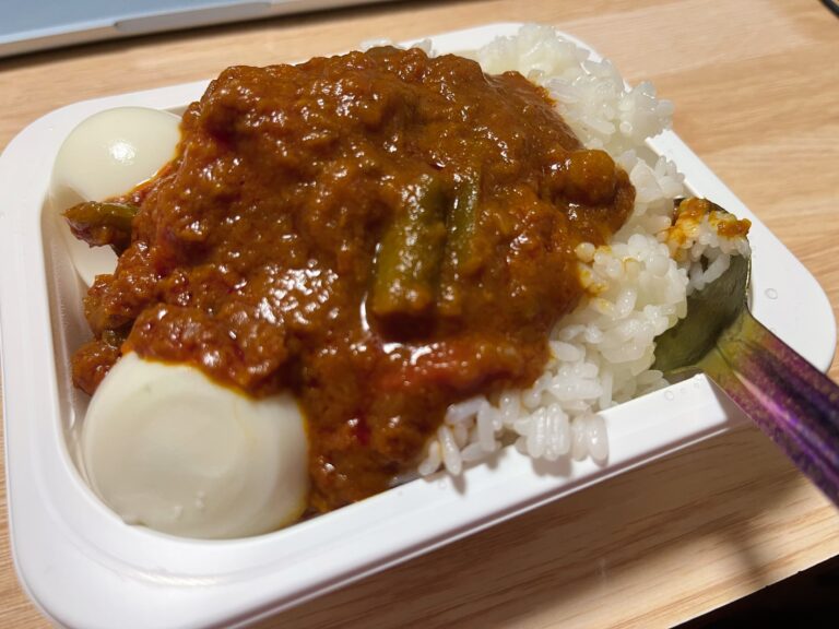Opgewarmde curry met rijst en ei. Samengepropt in de plastic rijstbak en gegeten met een spoon