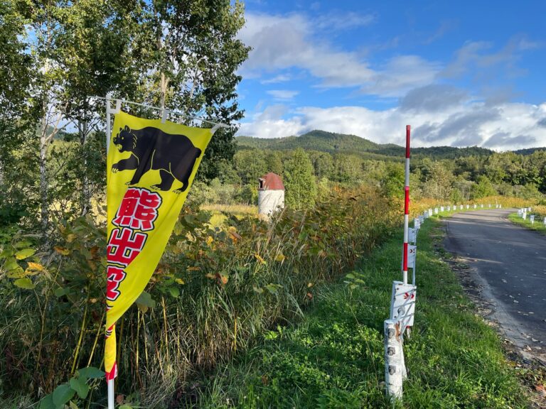 Waarschuwing voor beren. Deze keer in gele vlagvorm met daarop een zwart siloet van een boze beer en rode letters met wit zwarte randen