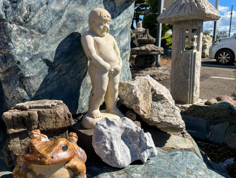 Een beeldje van een plassend mannetje tussen de grote rotsblokken