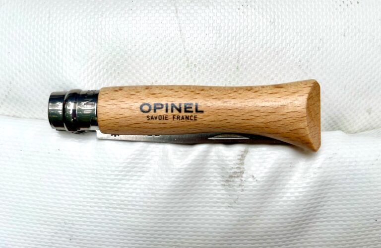 Een ingeklapt opinel zakmes met een houten handvat op een witte achtergrond