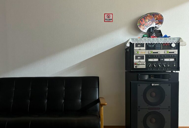 Een jaren tachtig cassettedeck met daaronder een enorme speaker 