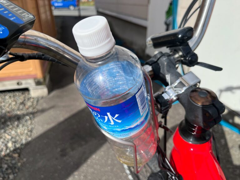 Leeg plastic transparant waterflesje aan die in een houder aan het stuur van de fiets hangt