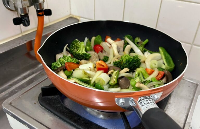 Een wokpan met groenten op een vuur