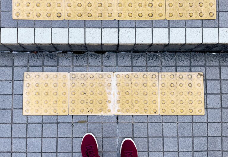 Een drap met kleine vierkante tegels met daarop de treden gele tegels met bobbels voor slechtzienden.