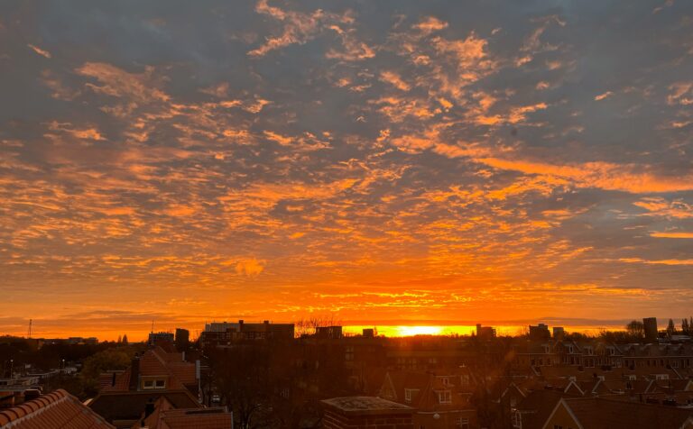 Opkomende zon kleurt de daken en de lucht fel oranje